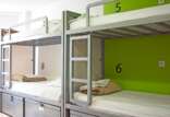 A clean and organized hostel room with numbered bunk beds, featuring crisp white bedding and storage lockers.